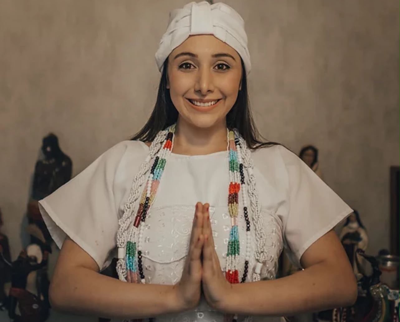 Mãe de Santo Sophia sorrindo com as mãos em prece